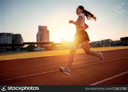 Asian Young fitness woman runner running on stadium track