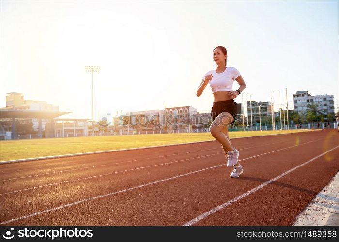 Asian Young fitness woman runner running on stadium track -healthy lifestyle and sport concepts