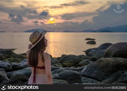 asian young girl standing on rock beach with sunset