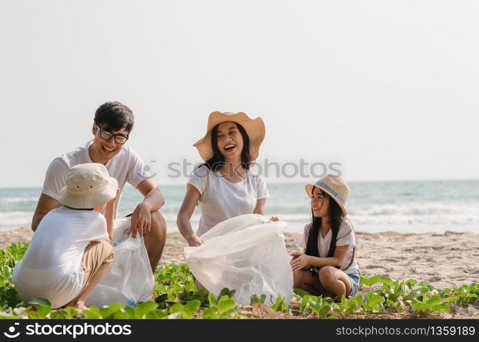 Asian young happy family activists collecting plastic waste on beach. Asia volunteers help to keep nature clean up and pick up garbage. Concept about environmental conservation pollution problems.