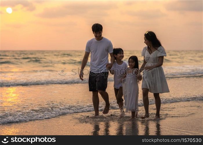 Asian young happy family enjoy vacation on beach in evening. Dad, mom and kid relax walking together near sea when sunset while travel holiday trip. Lifestyle travel holiday vacation summer concept.