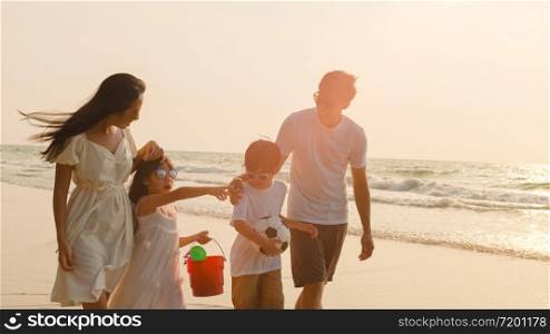 Asian young happy family enjoy vacation on beach in evening. Dad, mom and kid relax walking together near sea when sunset while travel holiday trip. Lifestyle travel holiday vacation summer concept.
