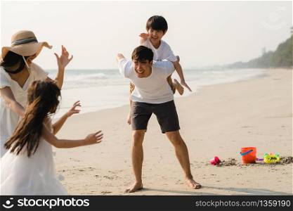 Asian young happy family enjoy vacation on beach in the evening. Dad, mom and kid relax playing together near sea when sunset while travel holiday. Lifestyle travel holiday vacation summer concept.
