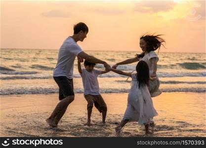 Asian young happy family enjoy vacation on beach in the evening. Dad, mom and kid relax playing together near sea when sunset while travel holiday. Lifestyle travel holiday vacation summer concept.