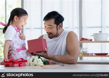 Asian young healthy dad with beard and little mixed race daughter opening gift box with exciting or surprising face. Family sitting at home kitchen celebrating father day or birthday special occasion