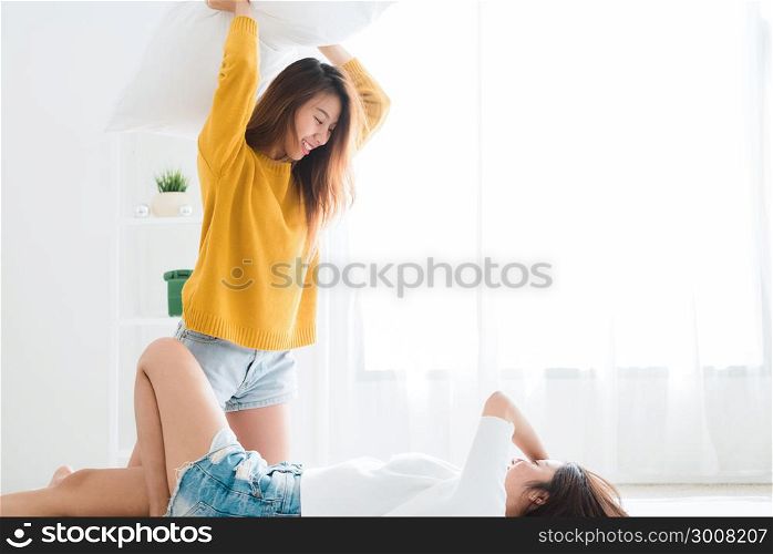Asian young lesbian couple playing to each other with love moment on the bed in bedroom surrounded with warm sunlight. LGBT couple have a love moment together ion the bed. LGBT love moment concept.