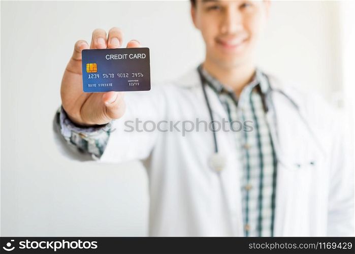 Asian Young man doctor therapeutic advising Abstract blur with focus show holding a credit card on bed in the room hospital background,payment medical treatment concept