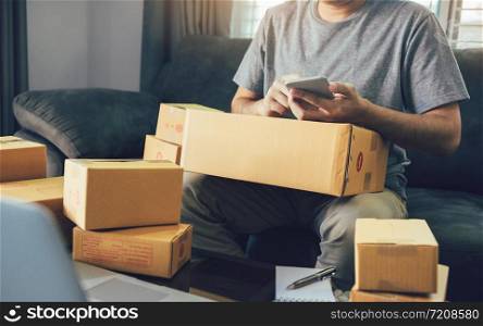 Asian young man using smart phone for checking shipment at home.