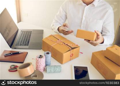 Asian young man using smart phone for checking shipment order at home.