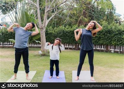 Asian young mother, father and child daughter practicing exercising stretching together before yoga workout outdoor morning in nature a field garden park. Happy family kid sport healthy lifestyle