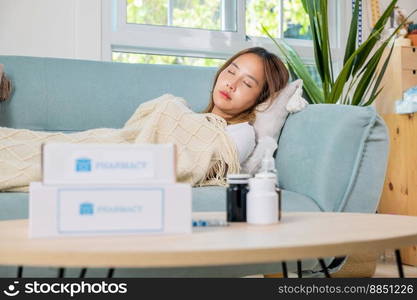 Asian young woman cold sick she sleeping and resting on sofa after take pills at home, beautiful female health problem use pharmacy kit box delivery service from hospital, delivery pharmacy concept