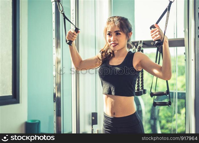 Asian young woman doing elastic rope exercises at cross fitness gym. Strength training and muscular. Beauty and Healthy concept. Sport equipment and Sport club center theme.