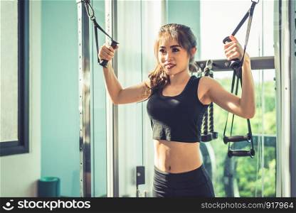 Asian young woman doing elastic rope exercises at cross fitness gym. Strength training and muscular. Beauty and Healthy concept. Sport equipment and Sport club center theme.