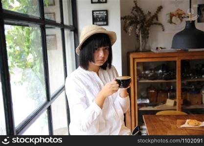 Asian young woman drinking coffee portrait with in coffee shop