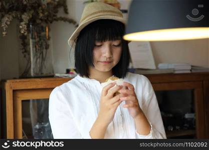 Asian young woman eating cookie portrait in coffee shop