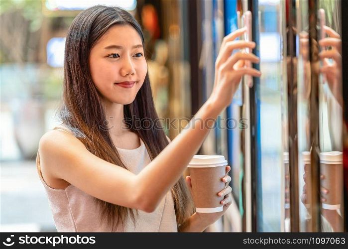 Asian young woman hand using smart mobile phone scanning the movie tickets machine for buy and get the coupon in department store,lifestyle and leisure,entertain and technology scanner concept