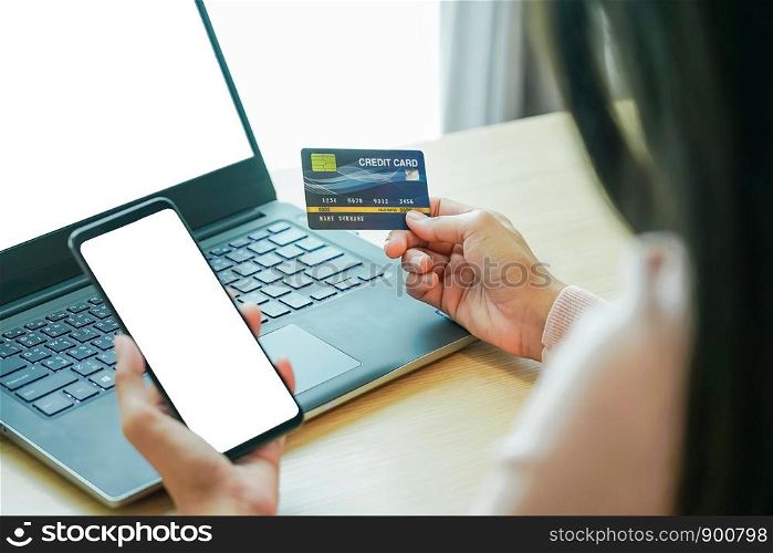 Asian young woman hands holding credit card and using laptop smartphone for online shopping concept