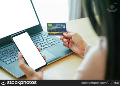 Asian young woman hands holding credit card and using laptop smartphone for online shopping concept