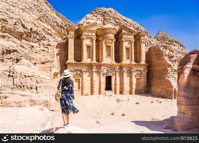 Asian young woman in colorful dress and hat enjoying at The Monastery, Petra's largest monument, UNESCO World Heritage Site, Jordan.
