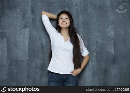 Asian young woman looking up standing by wall