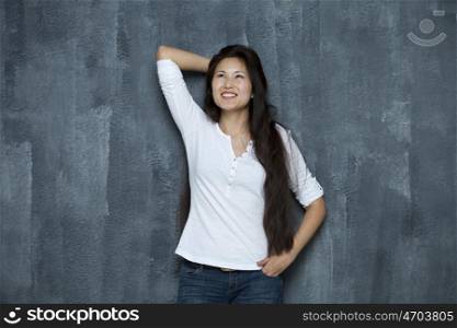 Asian young woman looking up standing by wall