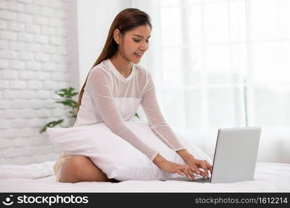 Asian young woman on bed using computer laptop for shopping online