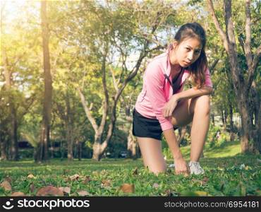 Asian young woman on mark to set ready for jogging exercise to buld up her body on glass in warm light morning. Young woman do exercise workout in park to make body beauty. Outdoor jogging in the park