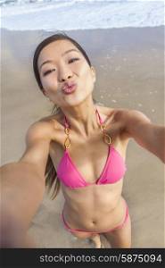 Asian young woman or girl in bikini, taking vacation selfie photograph at the beach