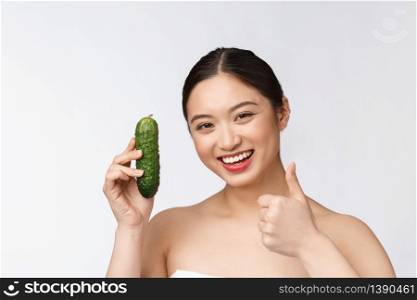 Asian young woman over isolated background holding cucumber. Asian young woman over isolated background holding cucumber.