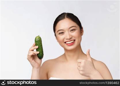 Asian young woman over isolated background holding cucumber. Asian young woman over isolated background holding cucumber.