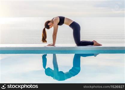 Asian young woman practice yoga Cow pose on the beach with beautiful sea in the morning,Feeling so comfortable and relax in holiday,Healthy Concept