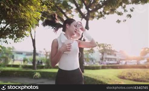asian young woman running in the park, using towel wiping sweat from face, during sunset diet nutrition health care insurance, self motivation tough girl run with beautiful sunset on the background