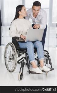 asian young woman sitting wheel chair looking man showing something laptop