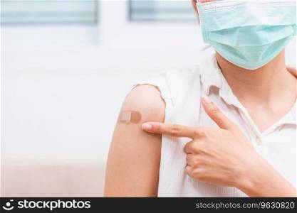 Asian young woman smile she is pointing to adhesive plaster on arm her vaccinated after getting immunity vaccine COVID-19 prevent