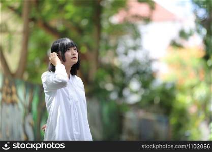 Asian young woman thinking and looking portrait with green tree background