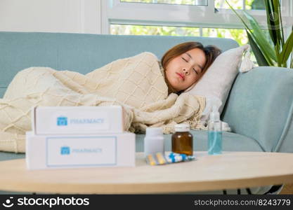 Asian young woman tired sick she sleep and resting on sofa after take medicines pills in living room at home, beautiful female use pharmacy first aid kit box delivery service from hospital, healthcare