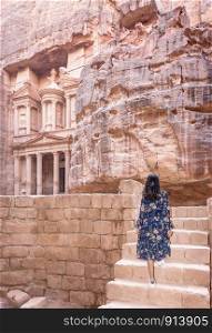 Asian young woman tourist in color dress and hat enjoying the Treasury, Al Khazneh in the ancient city of Petra, Jordan, UNESCO World Heritage Site