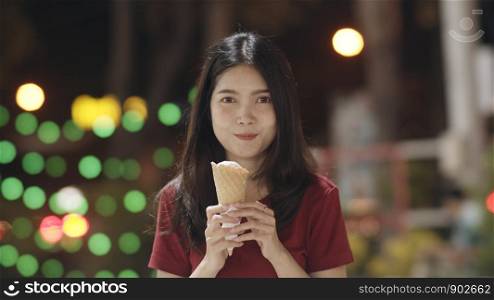 Asian young woman travel in Bangkok, Thailand, beautiful female feeling happy walking and eating ice cream at The Khao San Road. Women travel eat street food in Thailand concept.