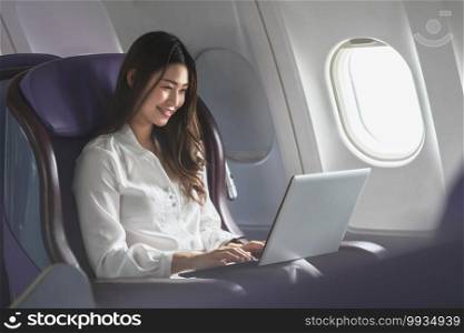 Asian young woman using laptop sitting near windows at first class on airplane during flight,Traveling and Business concept