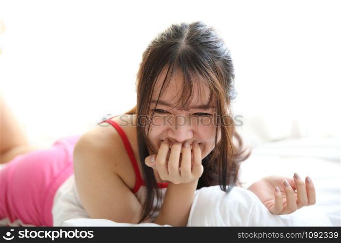 Asian young woman wake up on bed in white tone