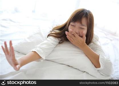 Asian young woman wake up with pillow in white room
