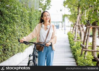 Asian young woman walking alongside with bicycle on summer in park countryside outdoor, Happy female smiling walk down the street with her bike on city road, ECO environment, healthy holiday travel