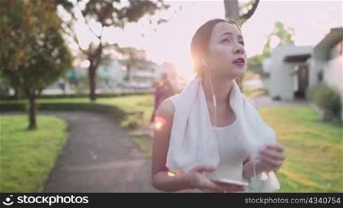 Asian young woman walking at the park after workout, life fitness wellness, self motivation, life insurance plan, healthy lifestyle, with sunset light behind, positive attitude happiness carefree