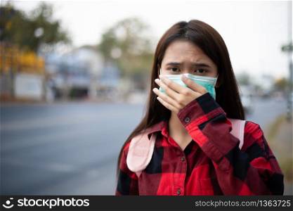 Asian Young woman walking in the city wearing face mask because of air pollution, particulates and for protection flu virus, influenza, coronavirus