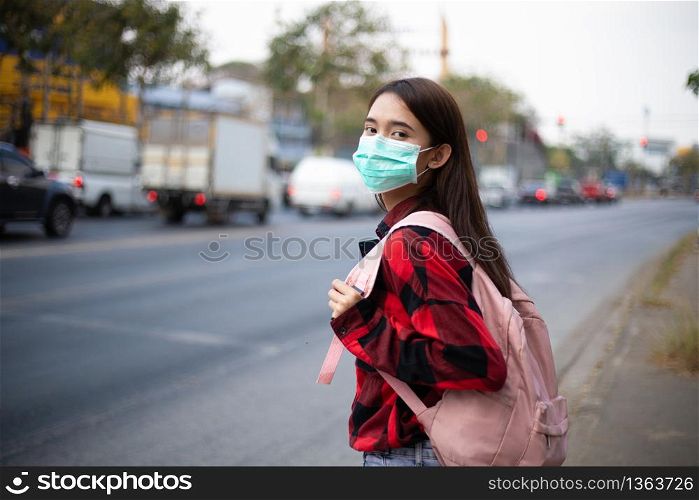 Asian Young woman walking in the city wearing face mask because of air pollution, particulates and for protection flu virus, influenza, coronavirus