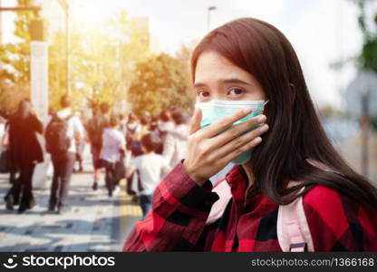 Asian Young woman walking in the city wearing protection mask on face because of air pollution, particulates and for protection flu virus, influenza, coronavirus