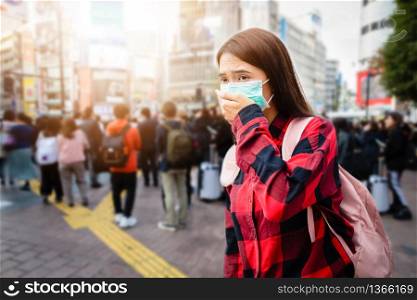 Asian Young woman walking in the city wearing protection mask on face because of air pollution, particulates and for protection flu virus, influenza, coronavirus