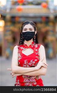Asian young woman wearing red cheongsam dress traditional decoration and wear protective mask germs for Chinese New Year Festival at shrine,Prevention of the spread of COVID-19 virus