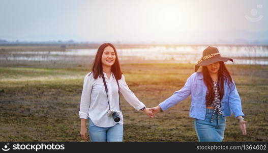 Asian Young women are having fun and laughing and hugging on the green field in the evening.