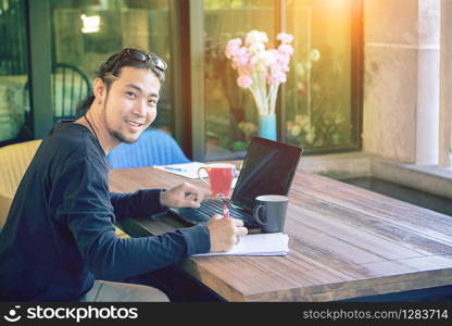 asian younger freelance man working at home office with computer laptop toothy smiling face